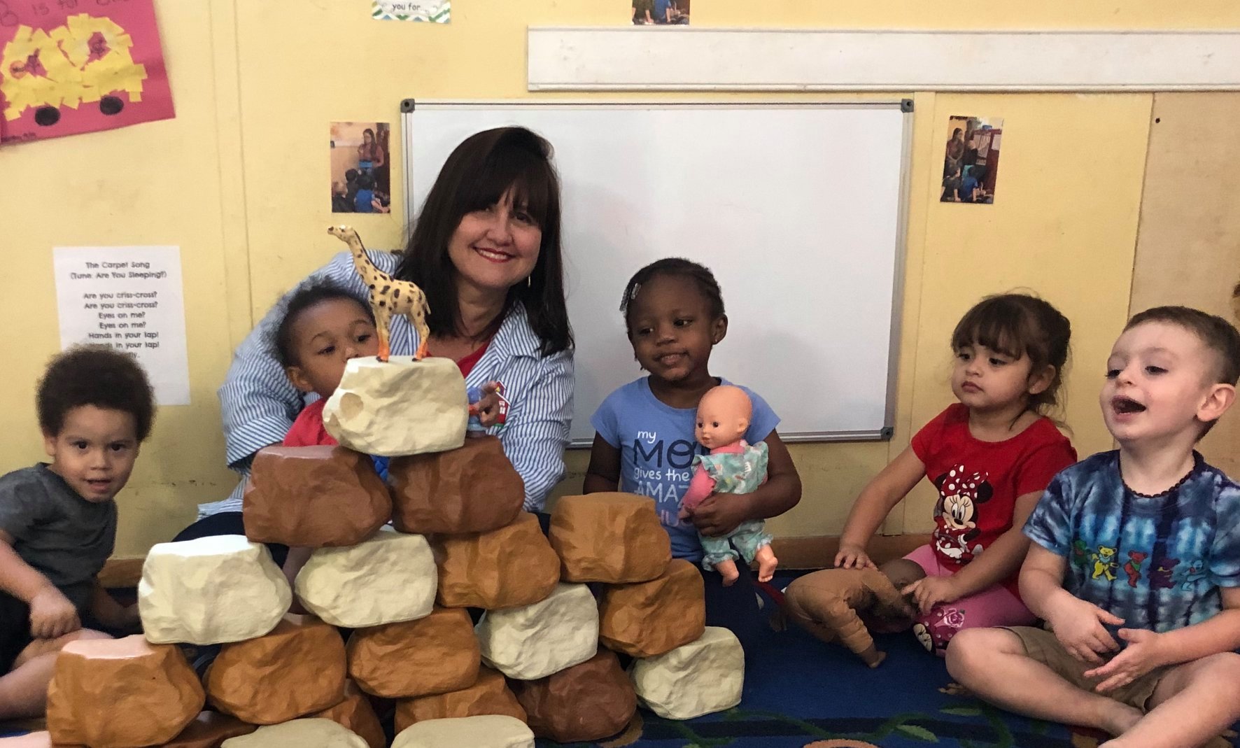 A photo of Mrs. Rosy, the owner, standing in front of My Little Red Schoolhouse